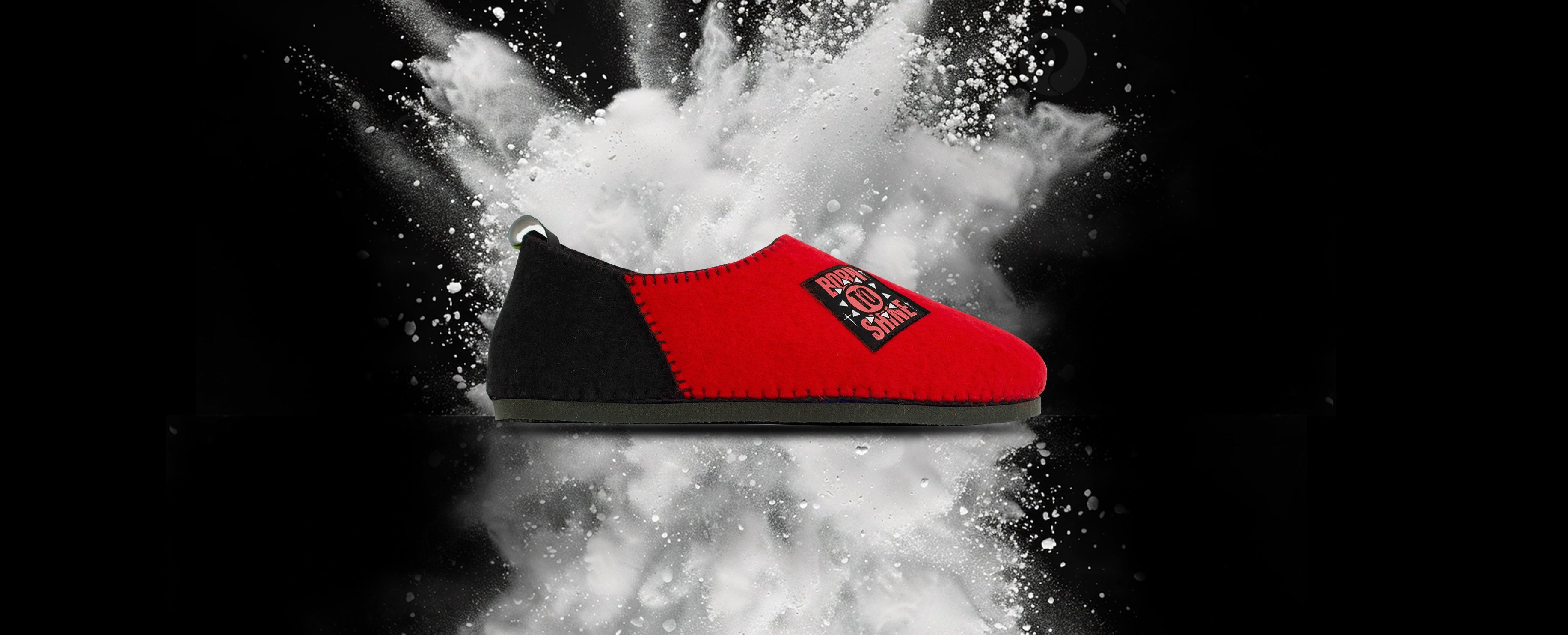 Red sneaker with a black sole on a black background with white powder effect